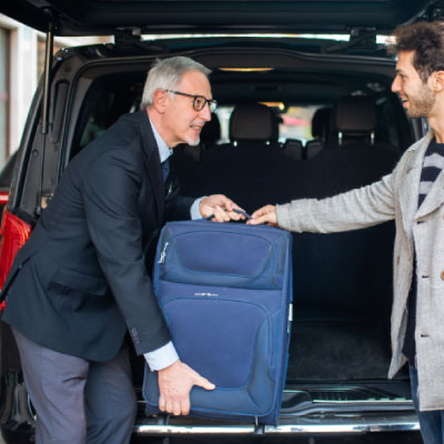 Professional chauffeur assisting with luggage at an airport transfer.